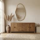De Spiegel Eldon gold hangt boven een houten dressoir in een lichte woonkamer met een vloerkleed - Richmond Interiors