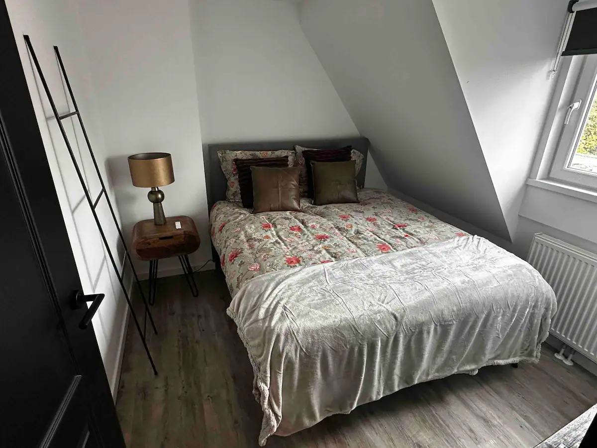 Slaapkamer 3 met tweepersoonsbed, nachtkastje en warme sfeerverlichting