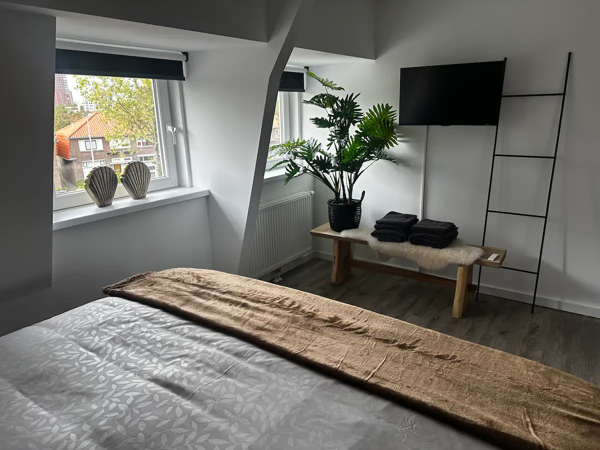 Slaapkamer voorzien van eigen flatscreen-tv, zwarte handdoeken en uitzicht op Enschede