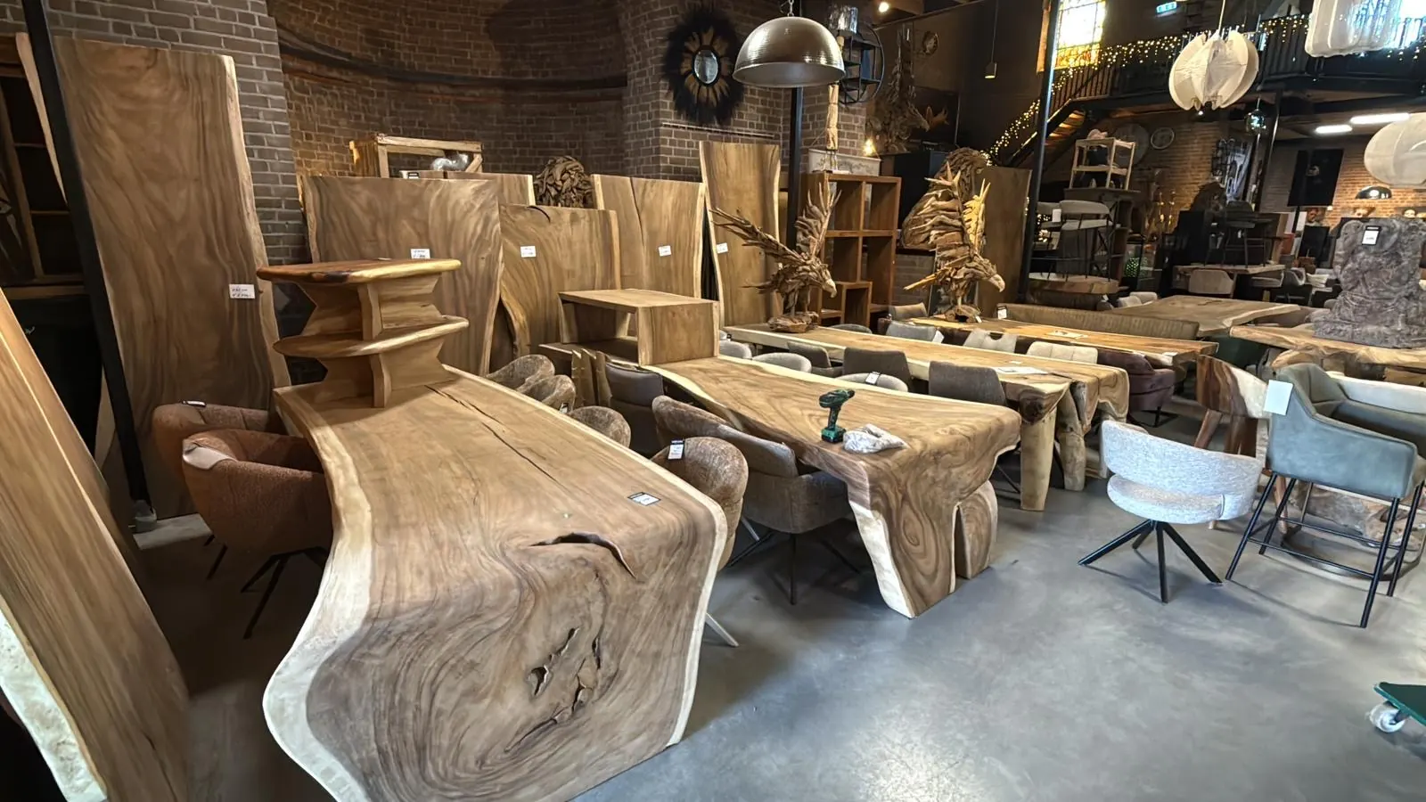 Voorraad suarhouten eettafels met natuurlijke boomrand in de showroom van Mokana