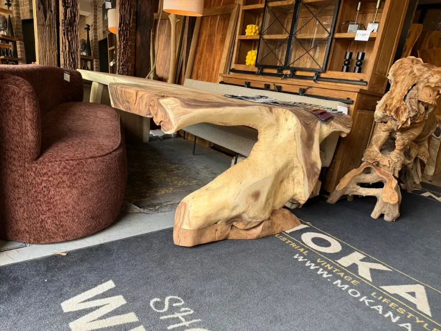 Suarhouten boomstamtafel met organische rand naast een roodbruine draaifauteuil